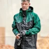 Mann trägt die grün-schwarze Elka Regenjacke im strömenden Regen – wetterfeste Arbeitsjacke mit Kapuze und hohem Kragen im Einsatz auf der Baustelle